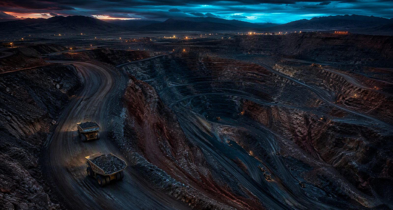 Open-pit mine with haul trucks at dusk